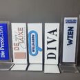 Tischaufsteller mit Markenlogos aus Acrylglas in Reihe nebeneinander